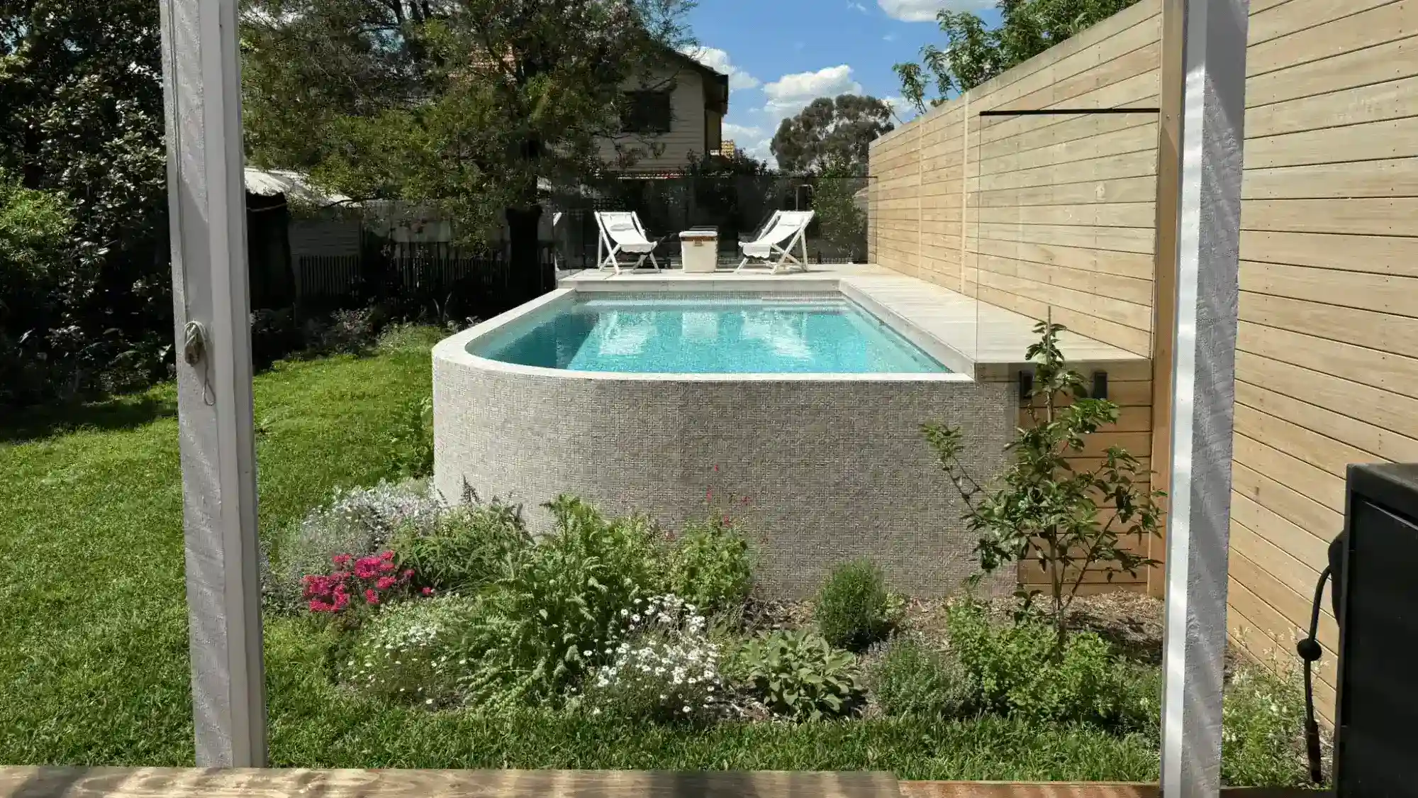 Beautiful backyard pool with garden and privacy fencing for relaxation.