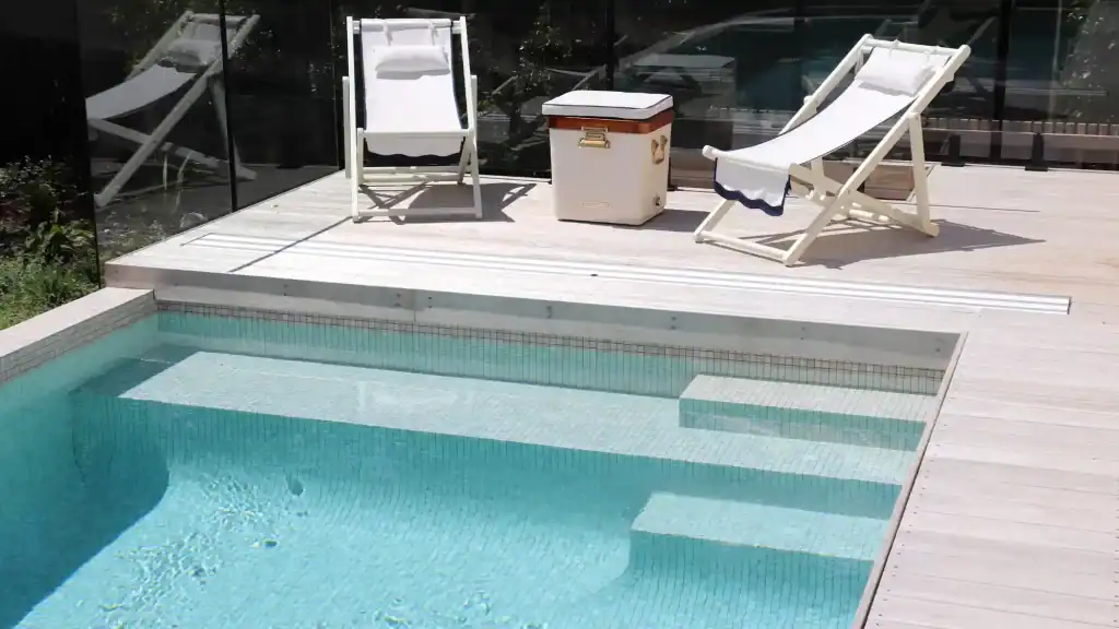 Luxury outdoor pool with sun loungers and deck area in a modern backyard setting.