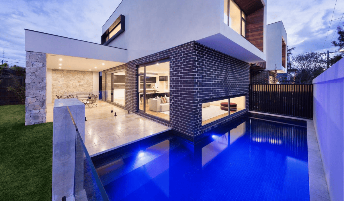 Modern house with illuminated swimming pool and outdoor living area.