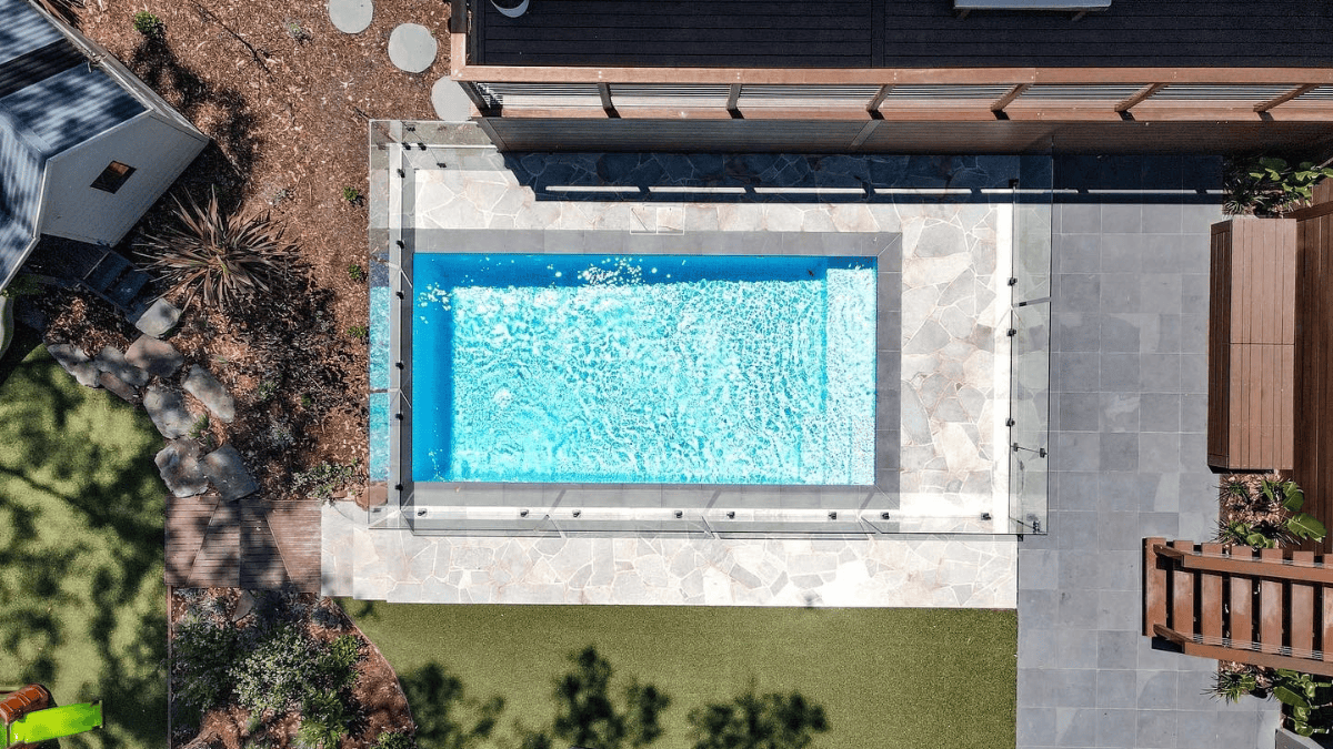 Aerial view of a modern backyard with a rectangular swimming pool and surrounding patio.
