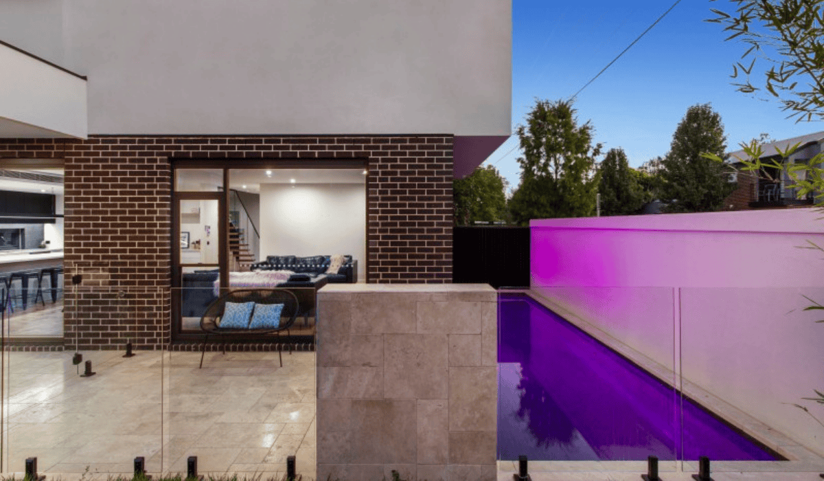 Modern backyard with illuminated purple pool and stylish outdoor living space.