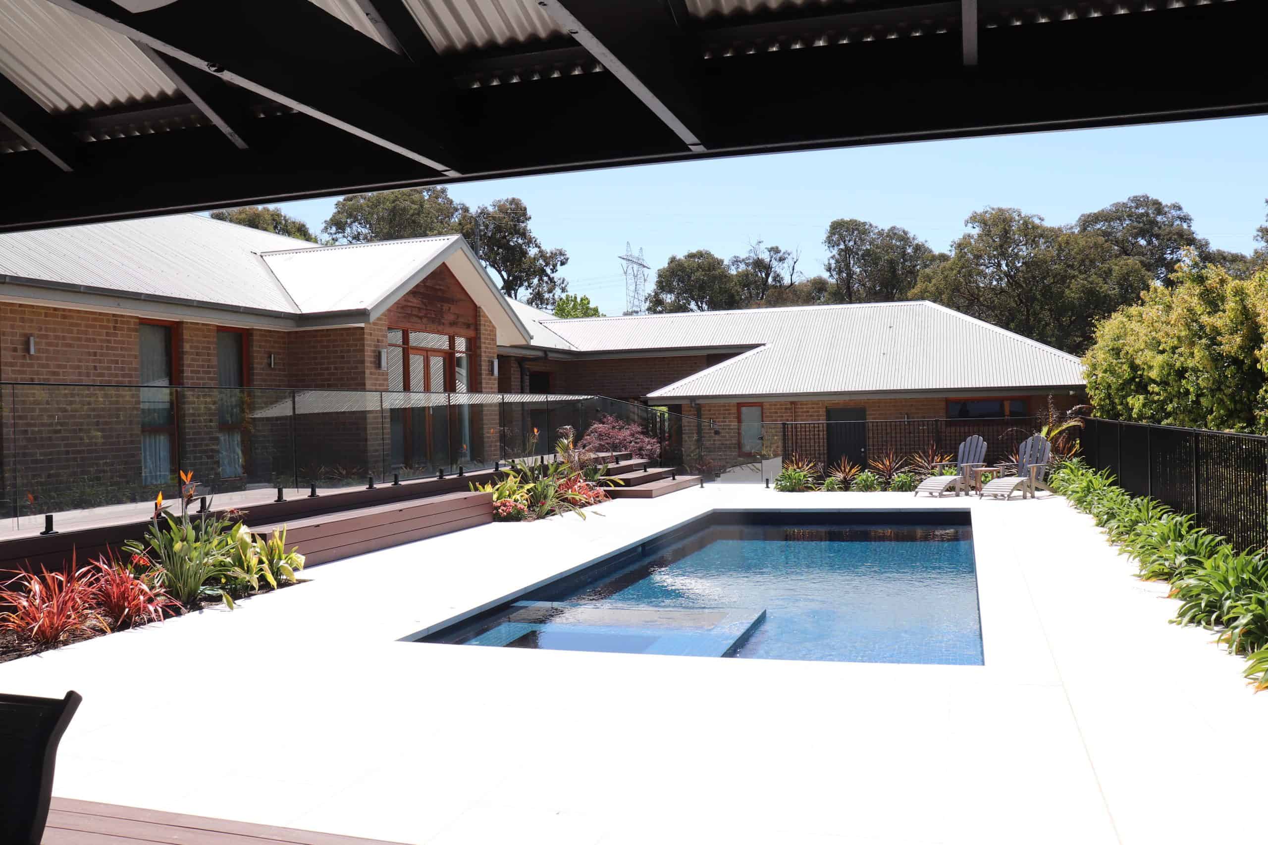 Modern backyard with a sleek rectangular pool and surrounding garden.