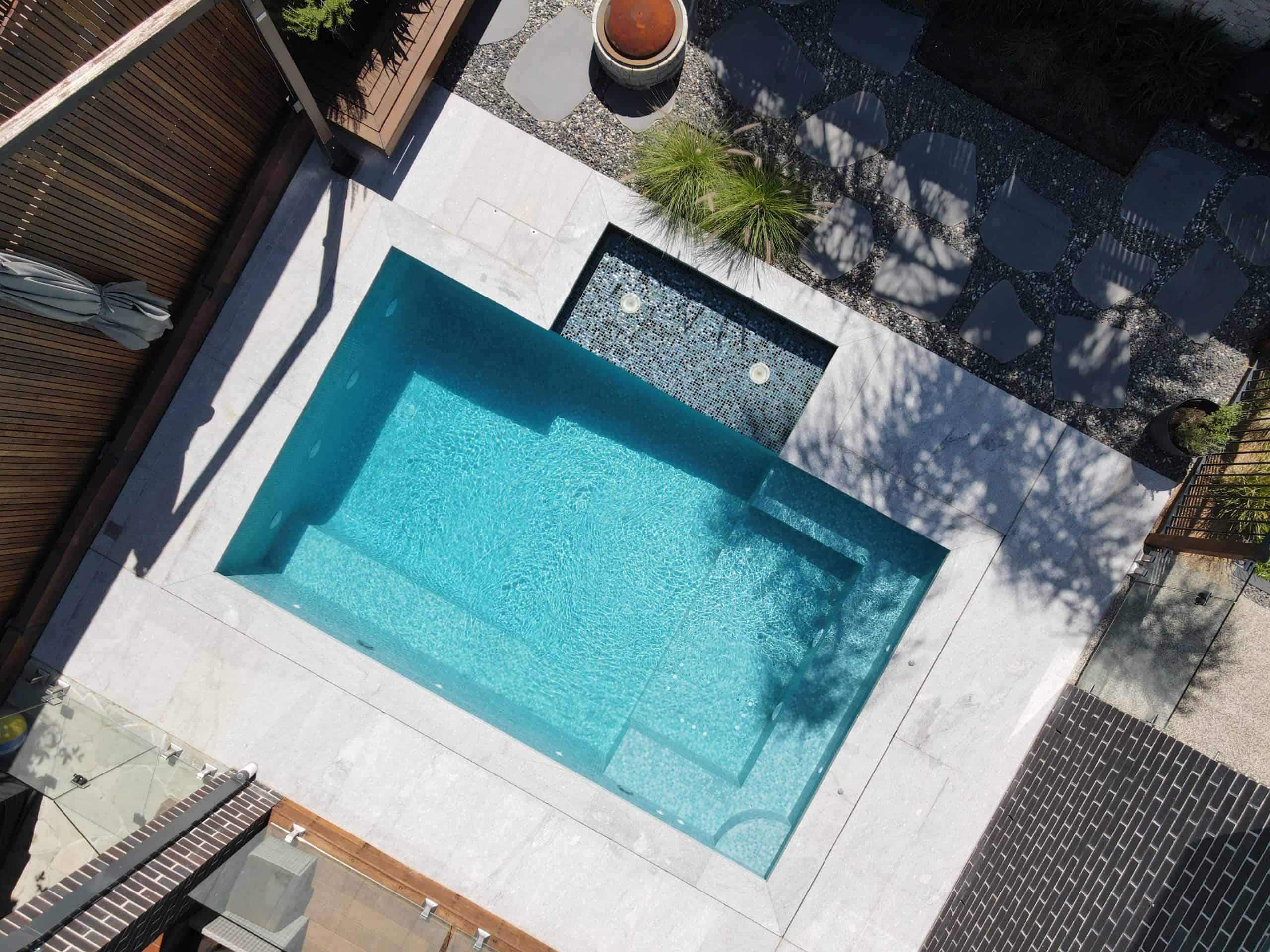 Modern rectangular in-ground swimming pool with surrounding deck and garden.
