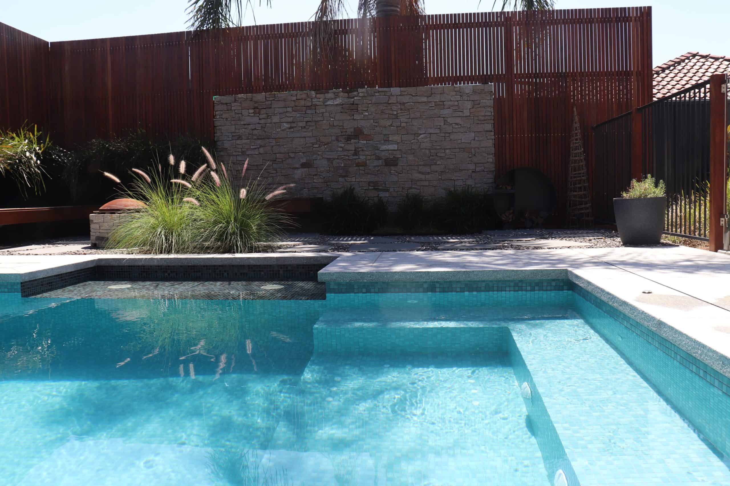 Modern backyard pool with stone feature wall and landscaped garden in South Morang.