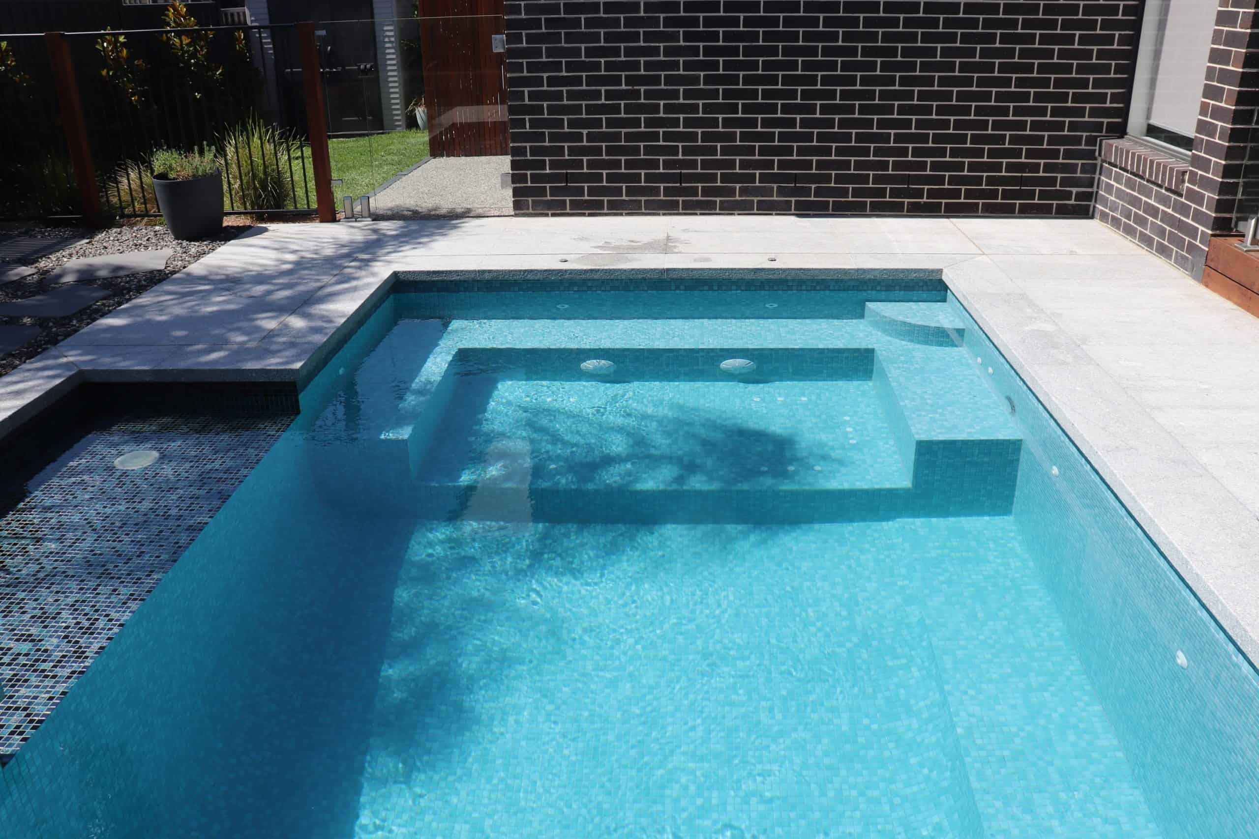 Modern backyard pool with built-in spa and surrounding paving in South Morang.