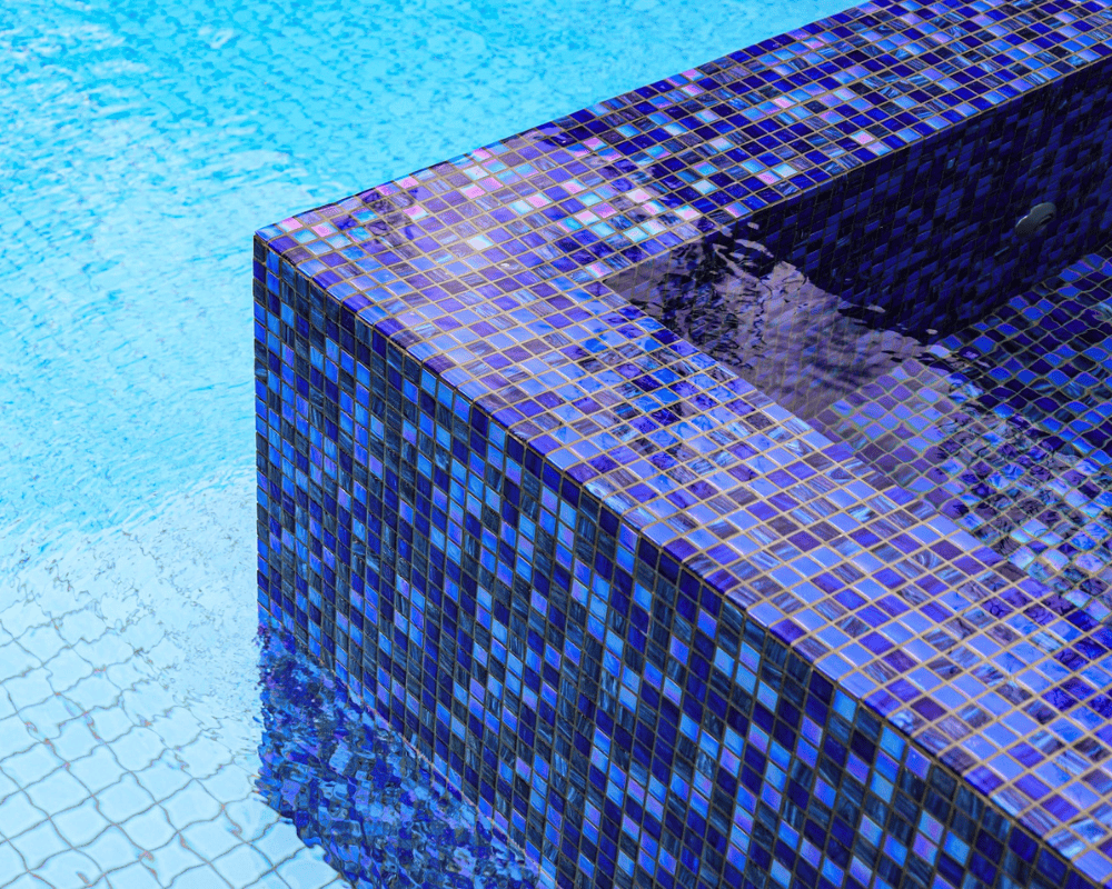 Close-up of a blue tiled pool edge with water cascading over the side.