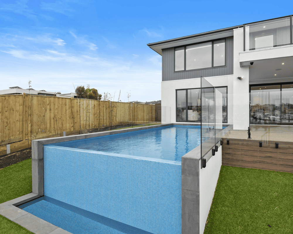 Modern concrete pool with glass fencing and backyard view in Australia.
